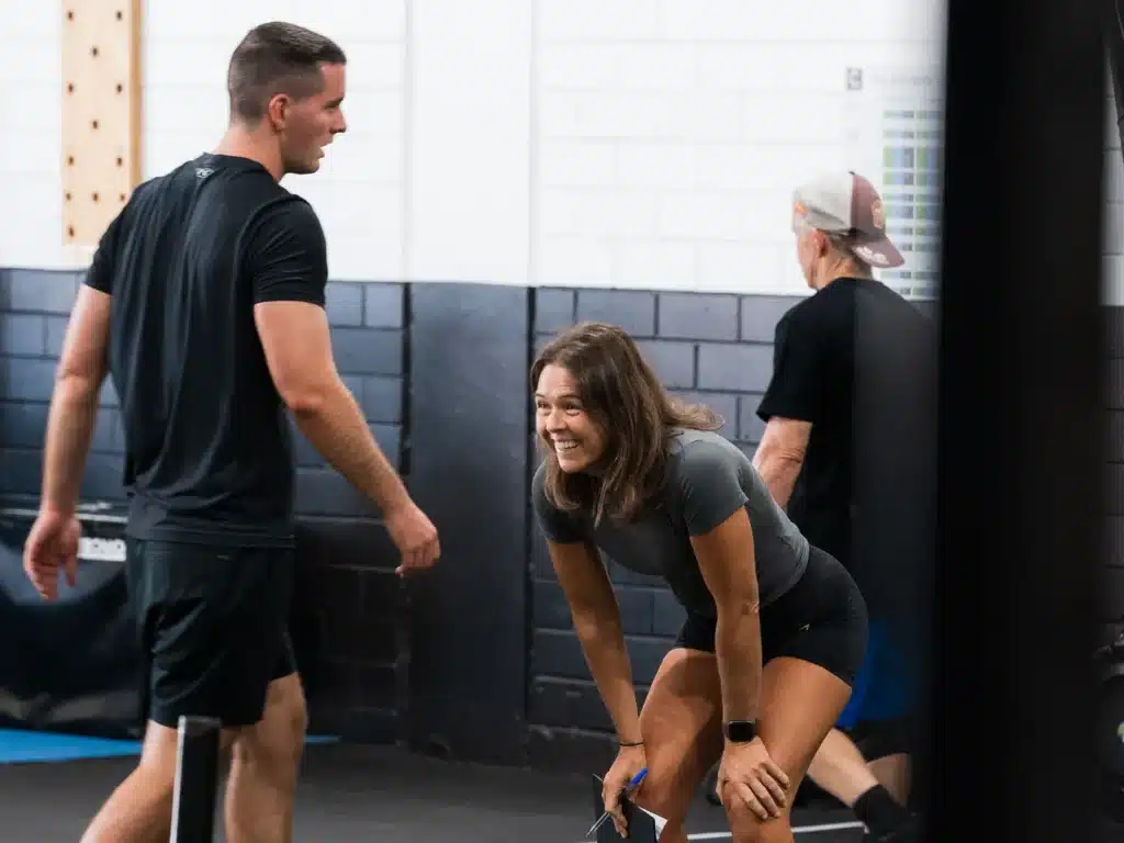 Cube Gym coach laughing with members on the gym floor during a class