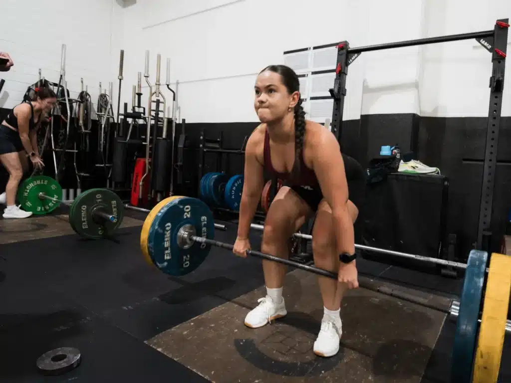 Cube Gym member setting up for a deadlift with a loaded barbell in the weights area